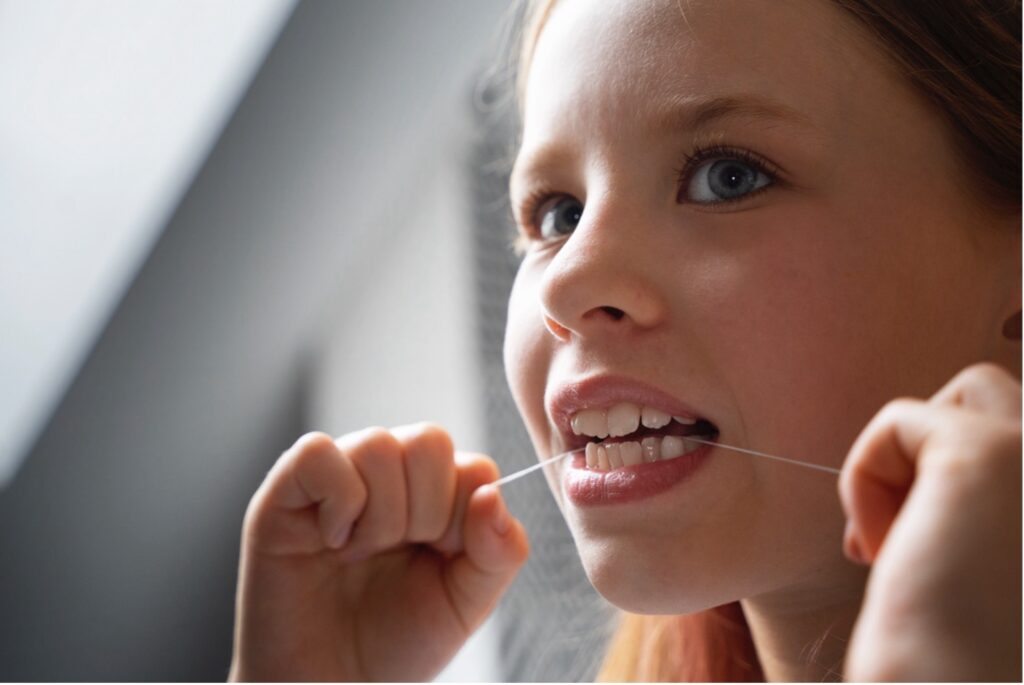Bambina che usa il filo interdentale – fotografia illustrativa Studio Dentistico Baldari