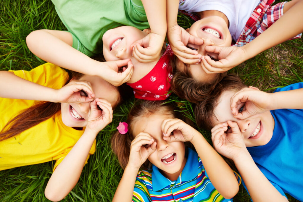 Ortodonzia intercettiva nei bambini: quando valutarla Gruppo di bambini sorridenti all’aperto, foto illustrativa della crescita e della salute orale.