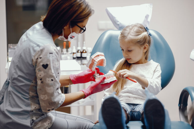 Bambina con una professionista durante una visita odontoiatrica, immagine illustrativa.