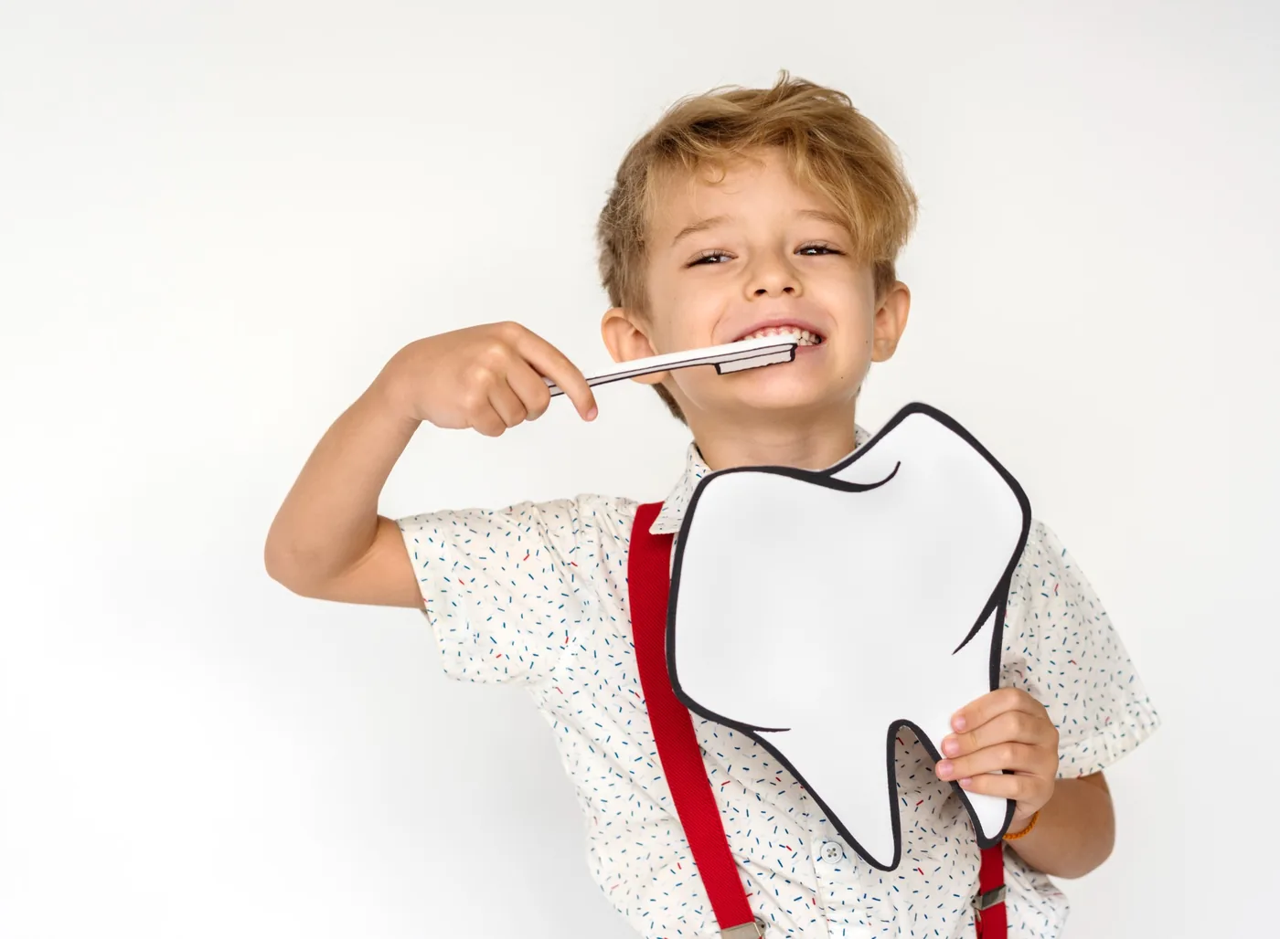 Bambino con spazzolino e sagoma di un dente, foto illustrativa per la guida sulla carie nei bambini dello Studio Dentistico Baldari.